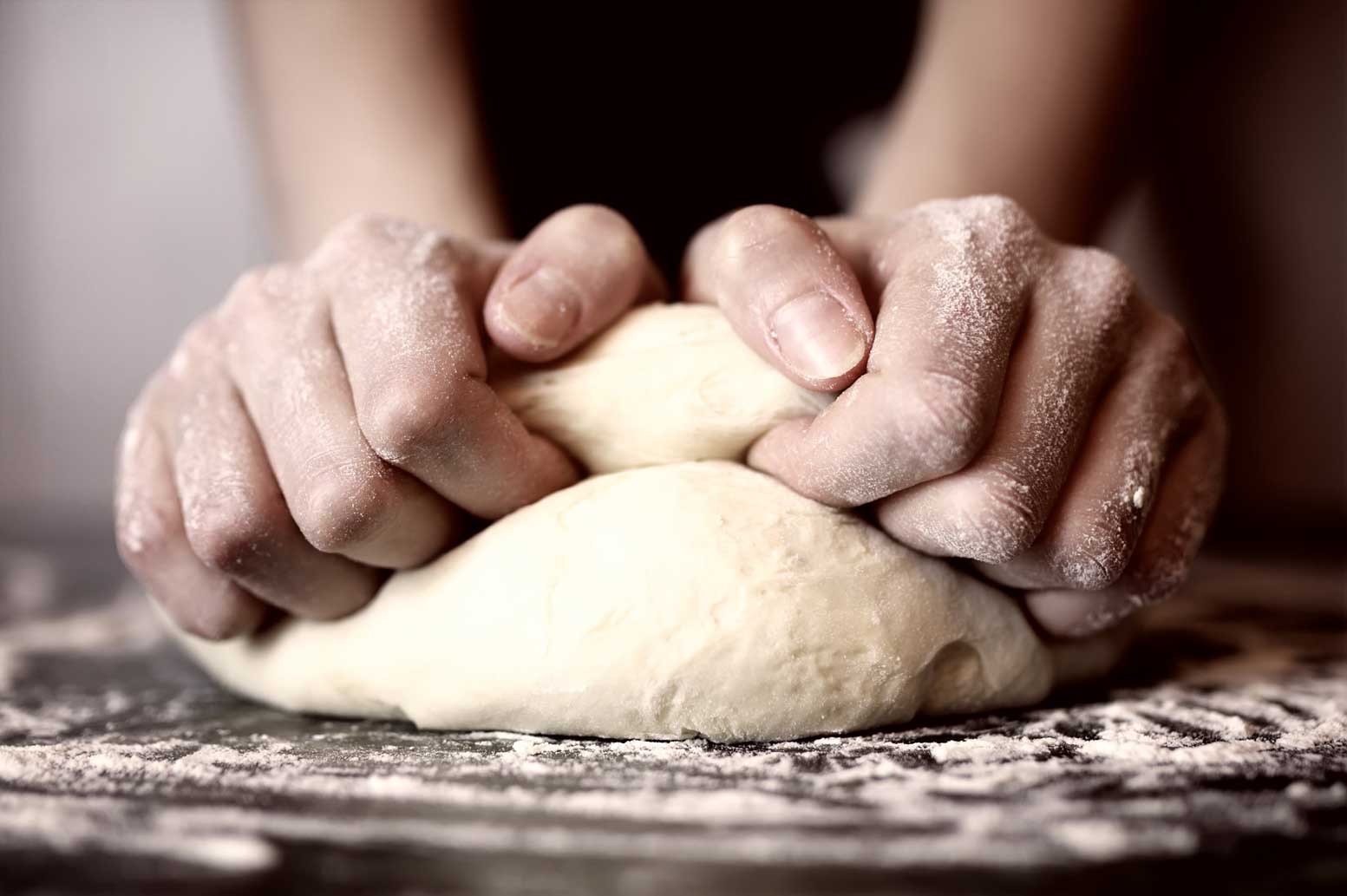 A person kneading dough with their hands